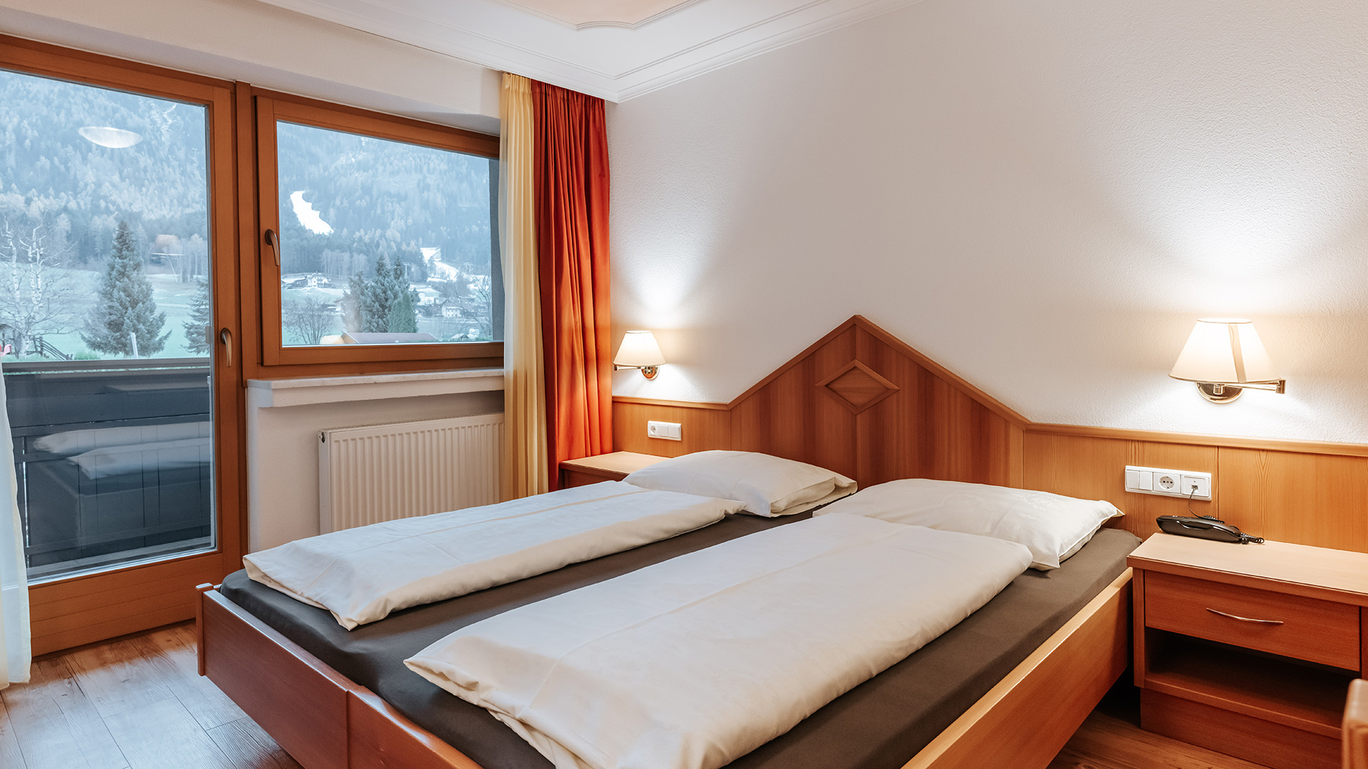 Accogliente camera doppia all'Hotel Tannenhof con elementi in legno, due letti e vista sul paesaggio montano del Plan de Corones.