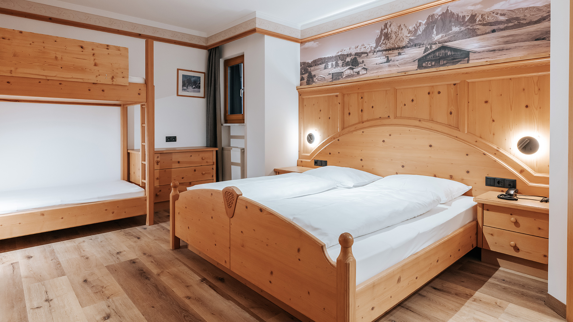 Accogliente camera familiare all'Hotel Tannenhof con letto matrimoniale, letto a castello, mobili in legno e panorama montano.