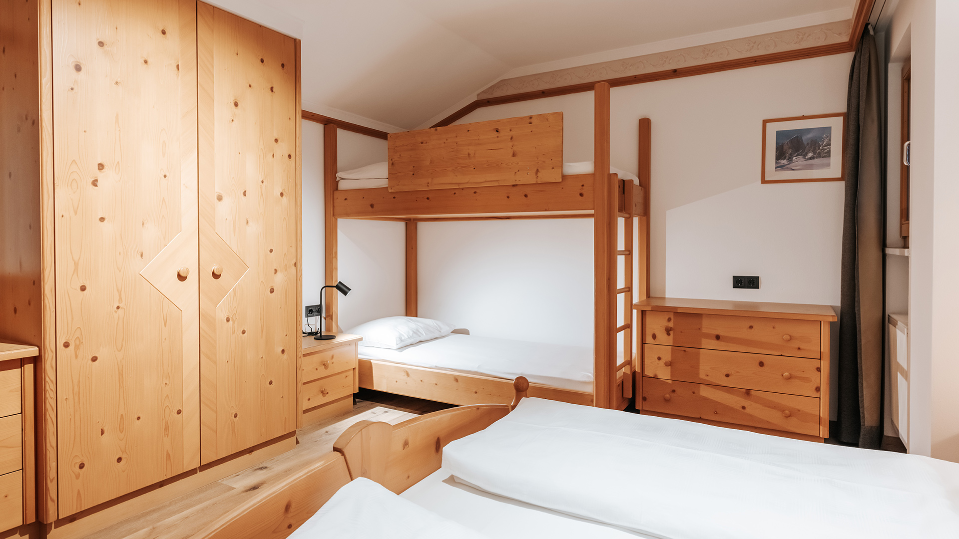 Accogliente camera familiare nell'Hotel Tannenhof con mobili in legno chiaro, letto a castello e letto singolo.