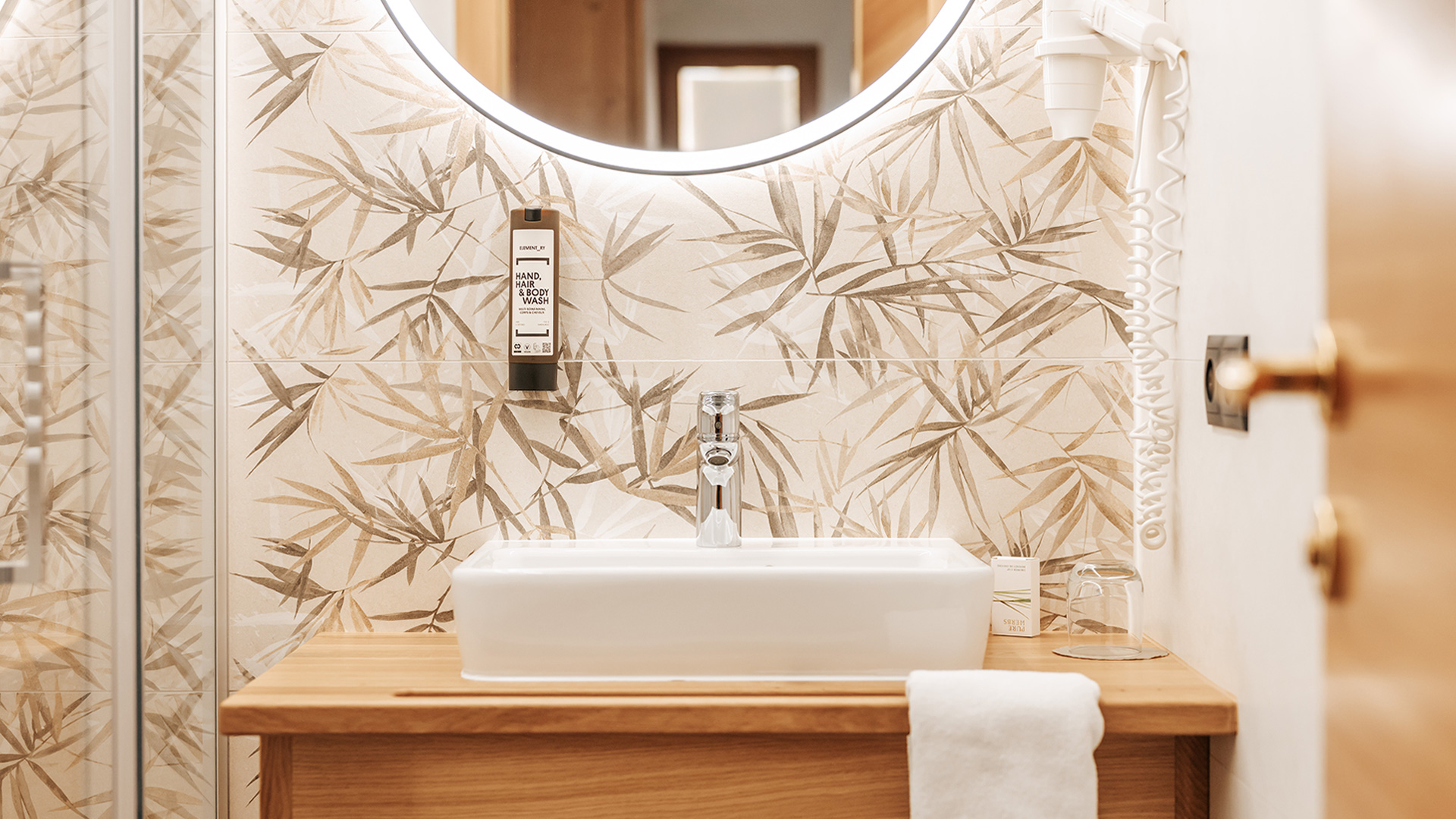 Bagno moderno nell'Hotel Tannenhof con lavabo, specchio illuminato e piastrelle in bambù.