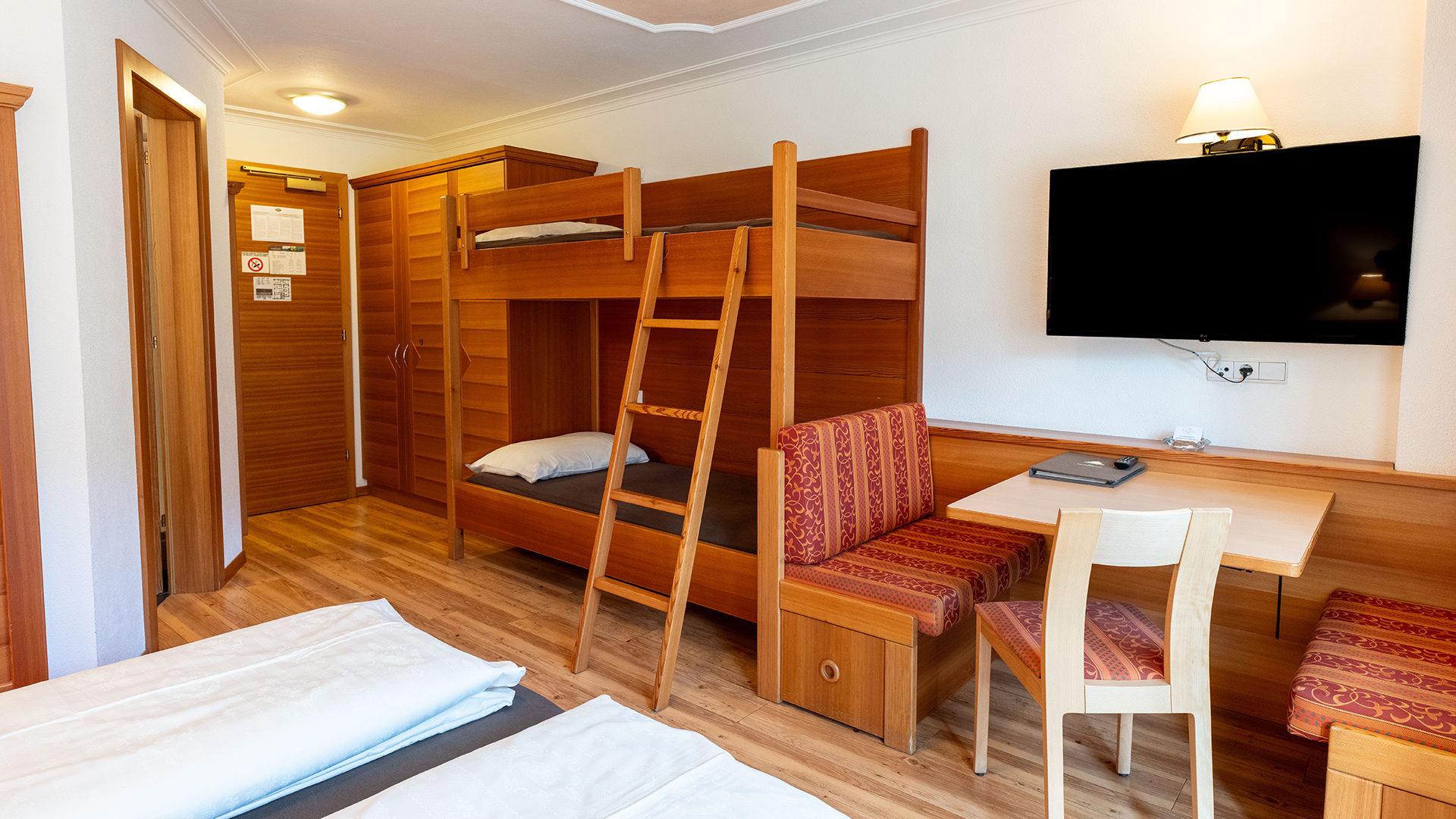 Accogliente camera familiare all'Hotel Tannenhof am Kronplatz con letto a castello, scrivania e TV.