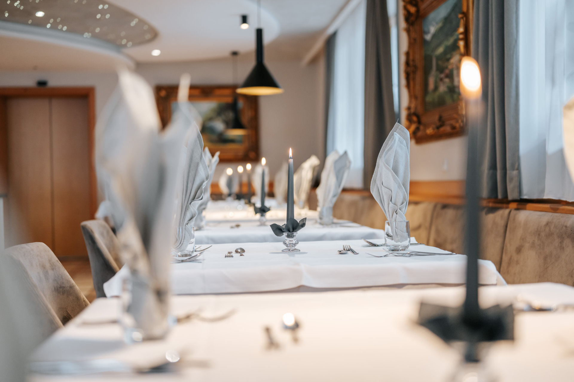 Tavolo festivamente apparecchiato nel ristorante dell'Hotel Tannenhof con luce di candela per una cucina deliziosa a Riscone.