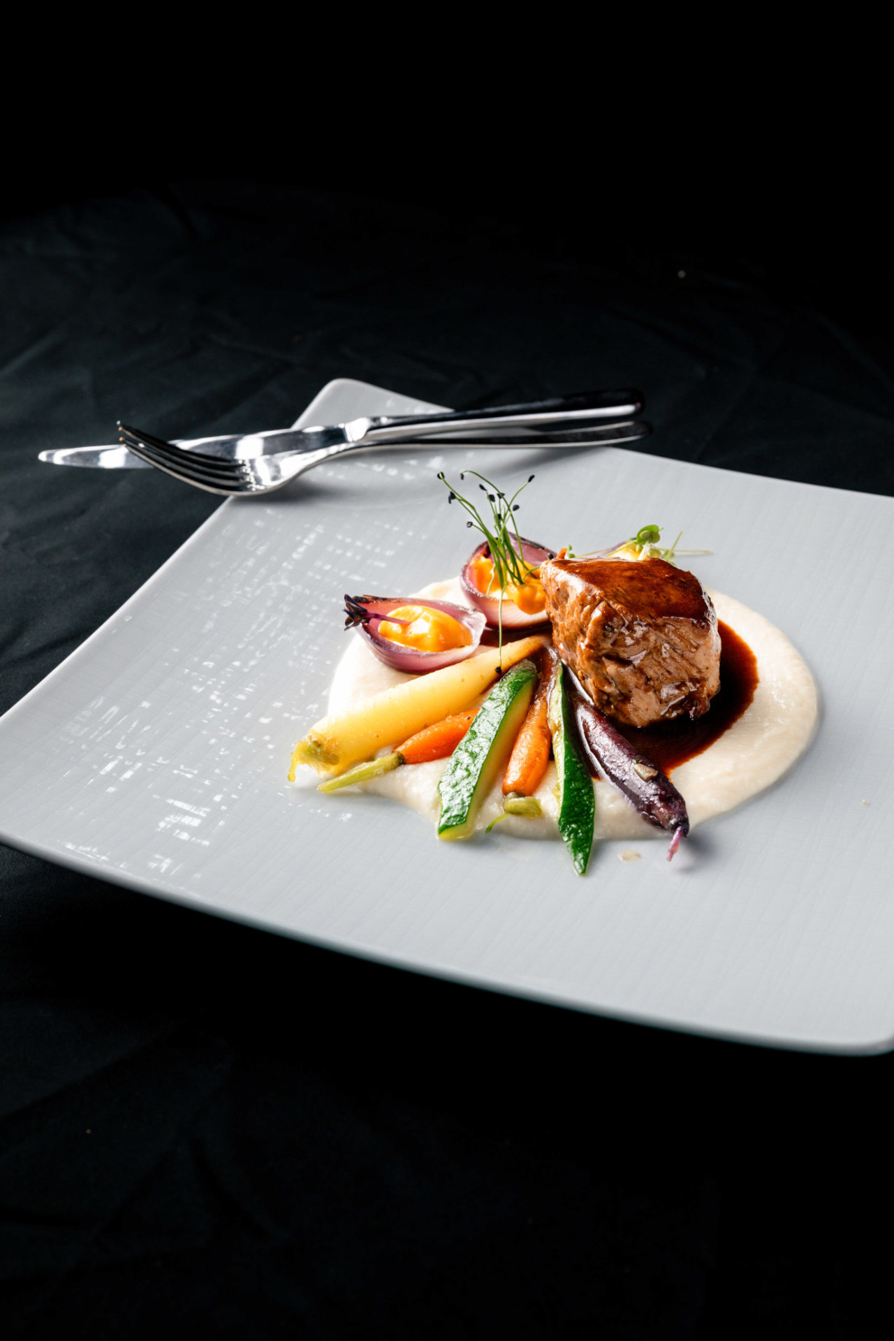 Un piatto preparato con arte a base di carne, verdure e purè, che mostra la cucina gourmet dell'Hotel Tannenhof a Reischach.