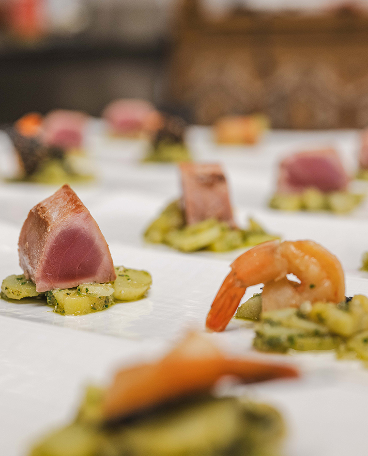 Primo piano di appetitosi stuzzichini con tonno e gamberetti, disposti su un piatto bianco, come esempio della cucina gourmet dell'Hotel Tannenhof.