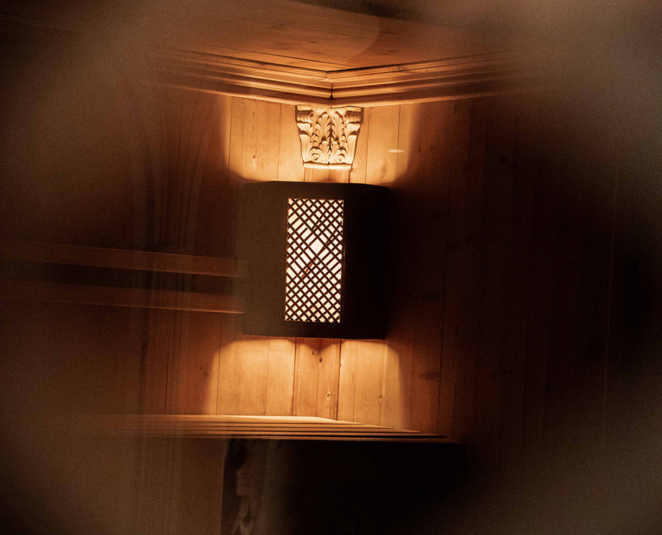 Stimmungsvolle Beleuchtung in der Wellnessoase des Hotel Tannenhof mit Holzvertäfelung und geschnitzter Verzierung.