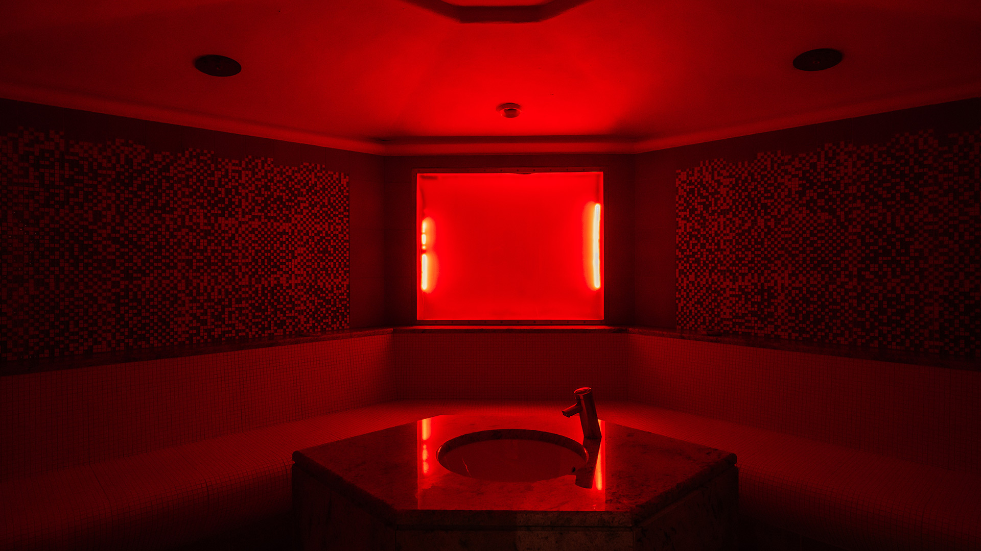 Rotes Dampfbad im Wellnessbereich des Hotel Tannenhof mit Mosaikfliesen, Waschbecken und Armatur.
