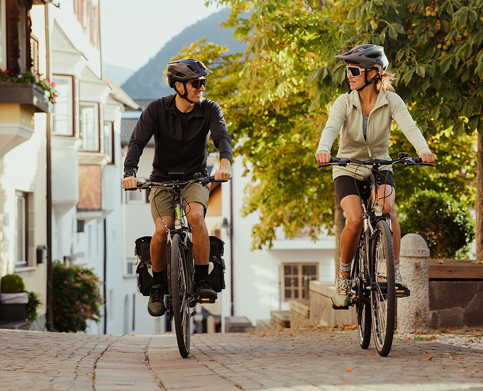 Couple cycling on a cobblestone road in South Tyrol, ideal for your summer holiday at Kronplatz.