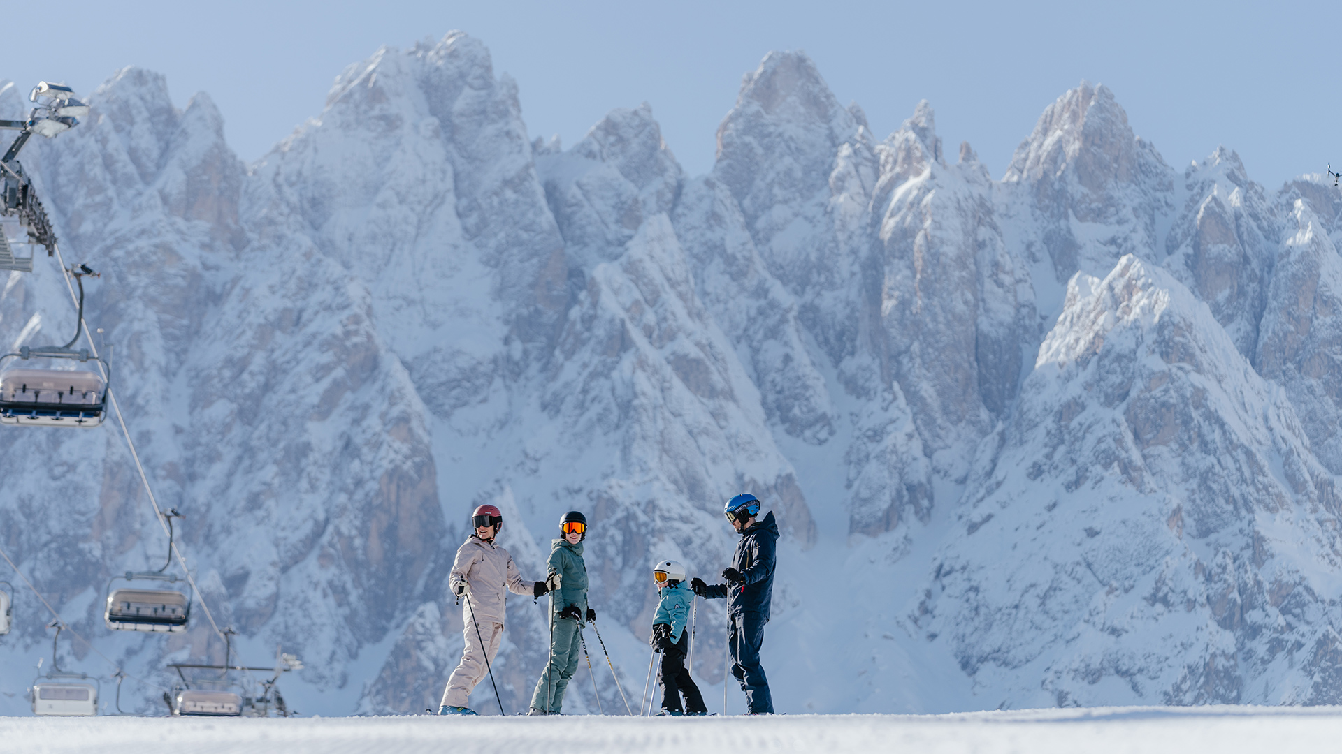 Family skiing at Kronplatz in front of majestic snow-covered mountains, ready for winter vacation.