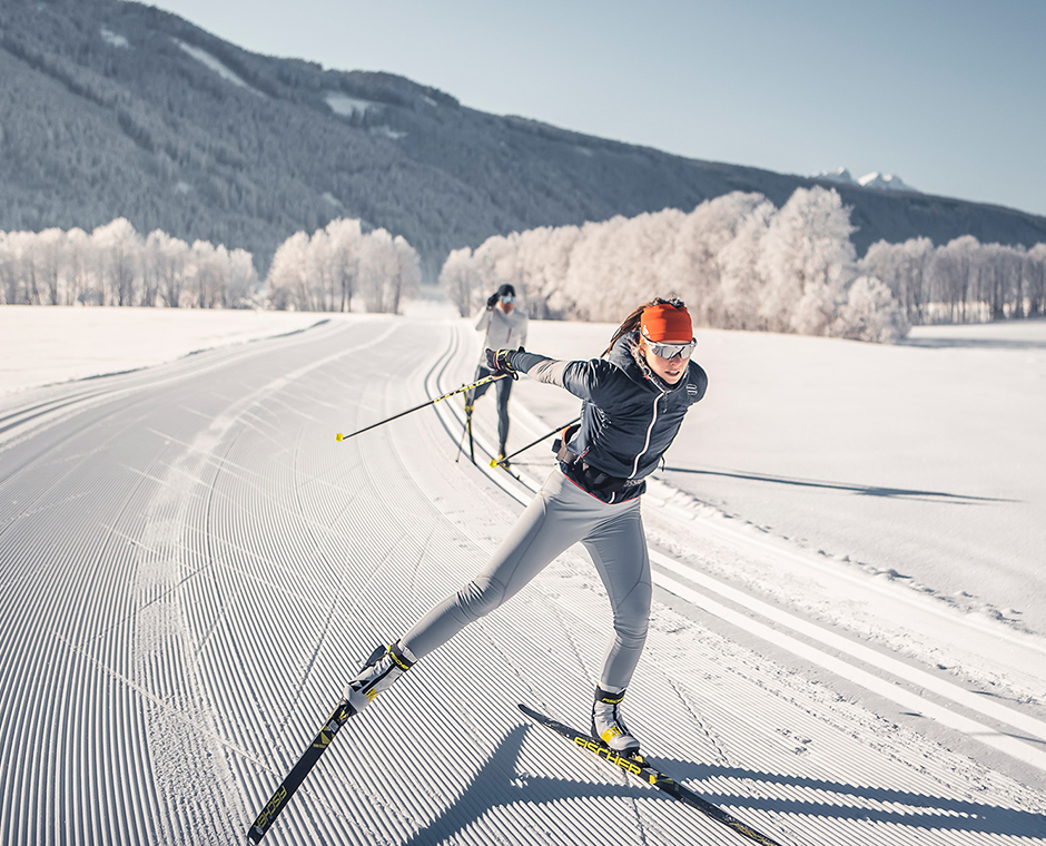 Two people cross-country skiing on a freshly groomed trail during a winter holiday at Kronplatz in South Tyrol.