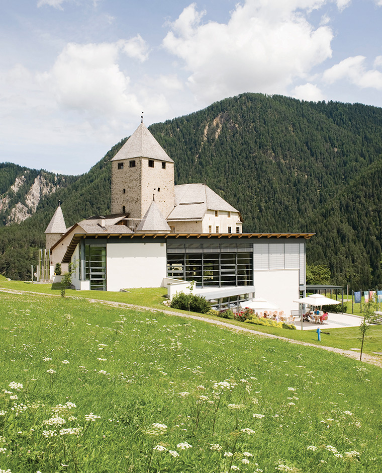 Das ladinische Landesmuseum Ciastel de Tor in St. Martin in Thurn, umgeben von grünen Wiesen und Bergen.