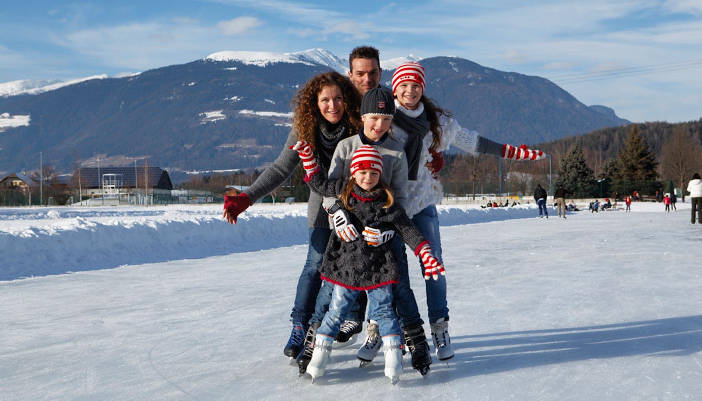 eine Familie, bestehend aus den Eltern und drei Kindern, beim Eislaufen