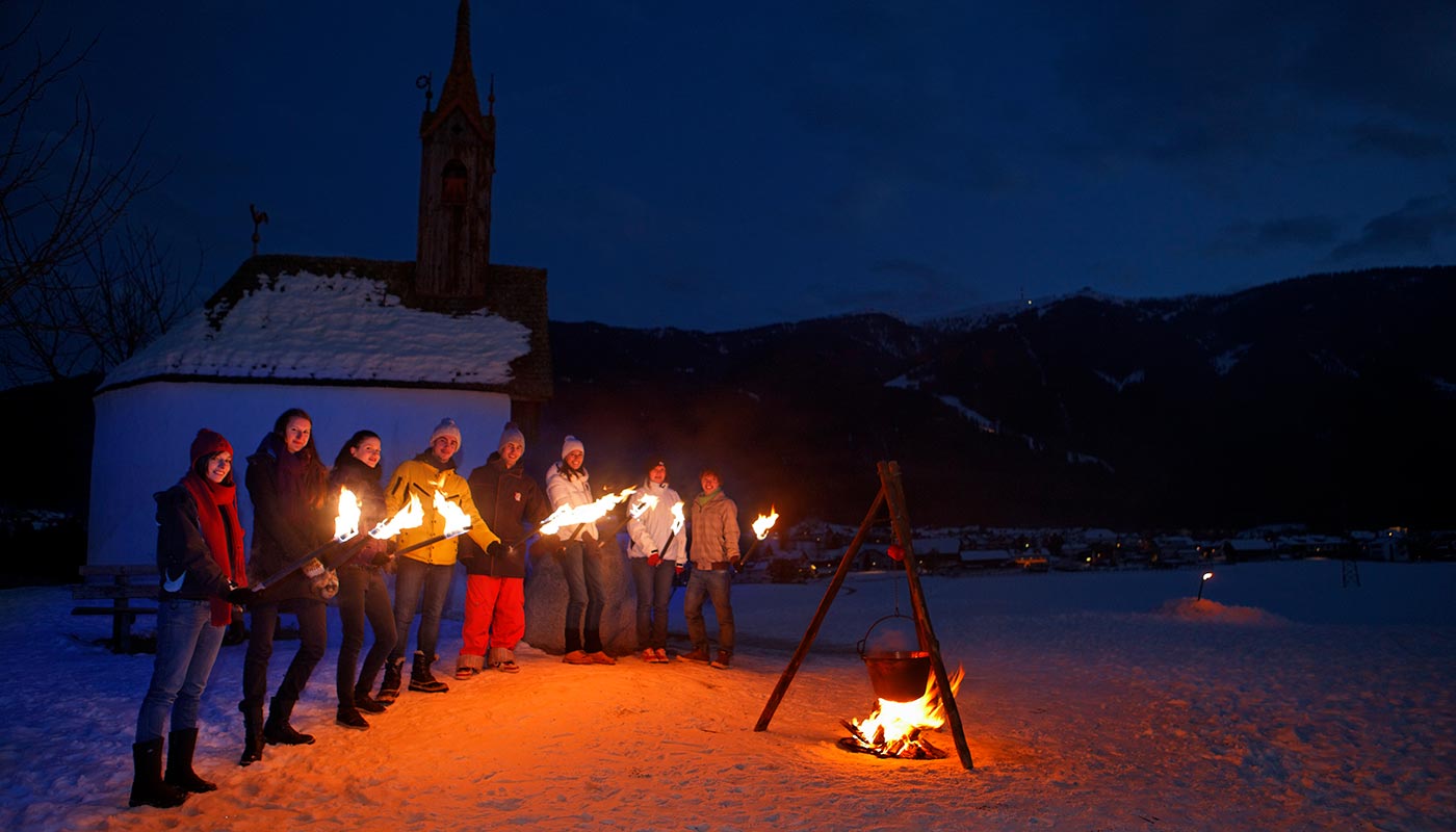 A group of tourists during the typical torchlight hike on the snow in Bruneck